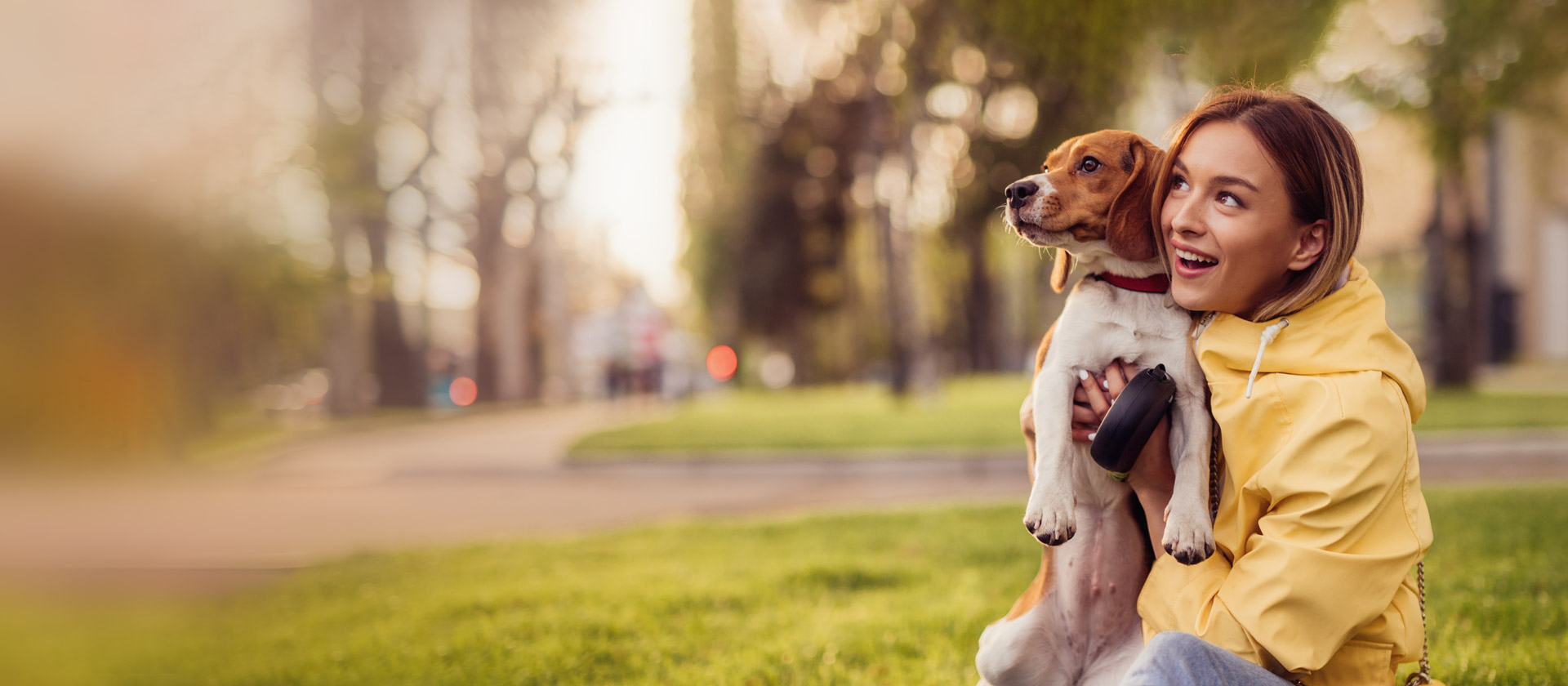 Eine Frau hält einen Hund im Gras und genießt die Zeit im Freien.